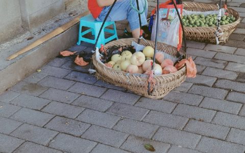 天气很热，有个小男孩在路边阴凉处卖水果